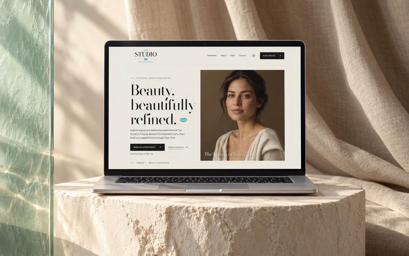 The Studio’s existing beauty website displayed on a laptop in an ivory, linen and sea-glass studio.