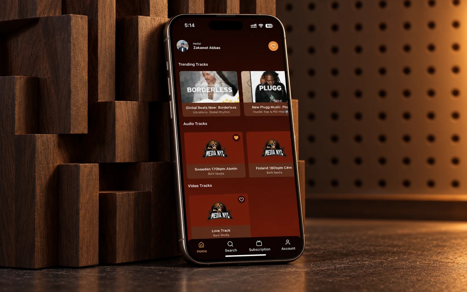 Bark Media’s existing music app on a phone against walnut acoustic panels with warm amber lighting.