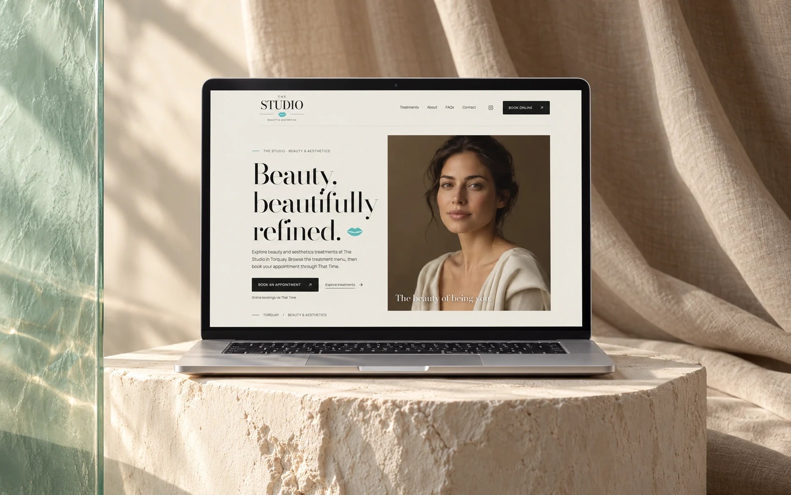 The Studio’s existing beauty website displayed on a laptop in an ivory, linen and sea-glass studio.
